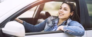 Young woman driving down the road with window rolled down