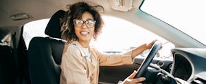 Smiling young woman wearing glasses driving a car