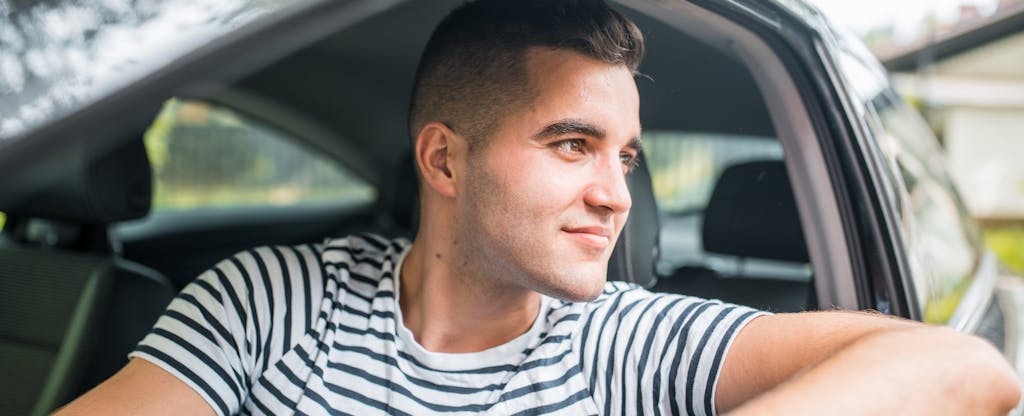 Man driving his car, smiling and looking out the window