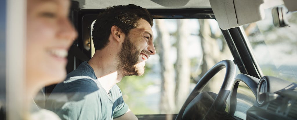 Smiling couple in car, going on a road trip