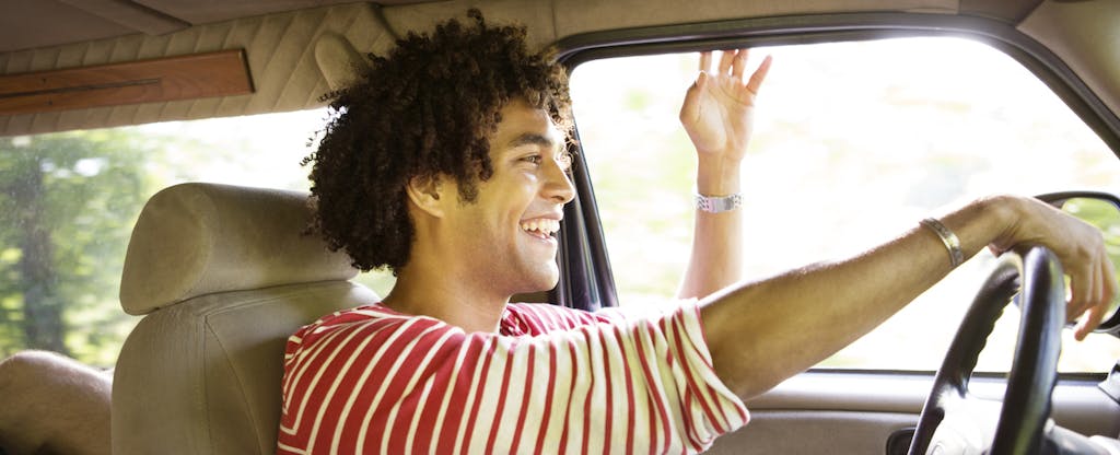 Happy man driving car that he insured with farmers auto insurance