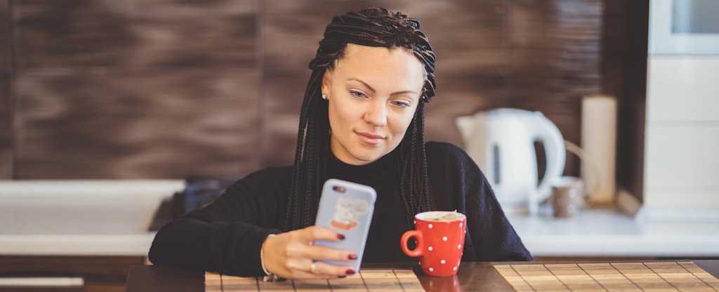 Young woman on cellphone, looking up elan financial on her credit reports