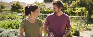 Man and woman standing outside in their garden, discussing getting a loan from Possible Finance