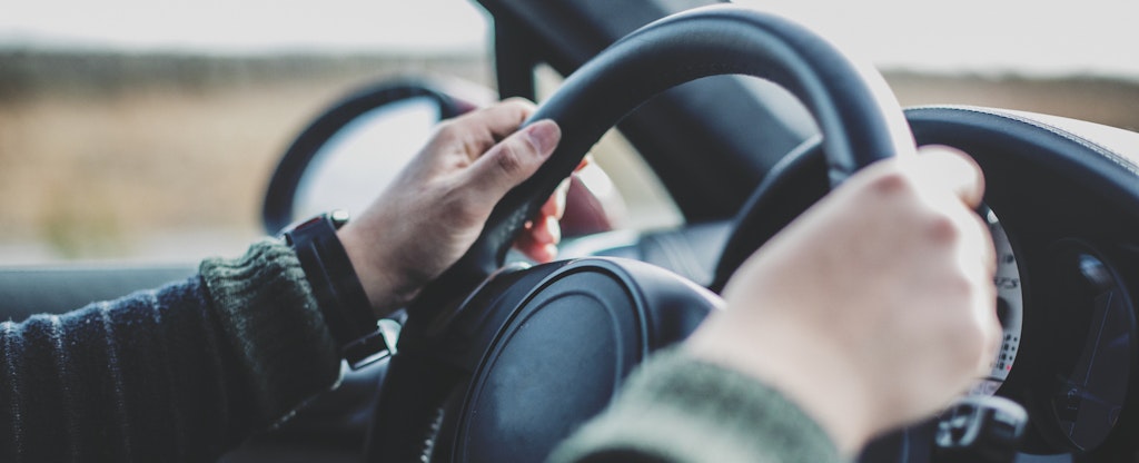 Close-up of man's hands on a car steering wheel