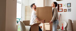 Couple carrying a big box together, moving into their new home