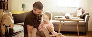 Smiling father holding young daughter in living room