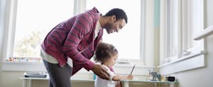 Smiling father helping young daughter with homework