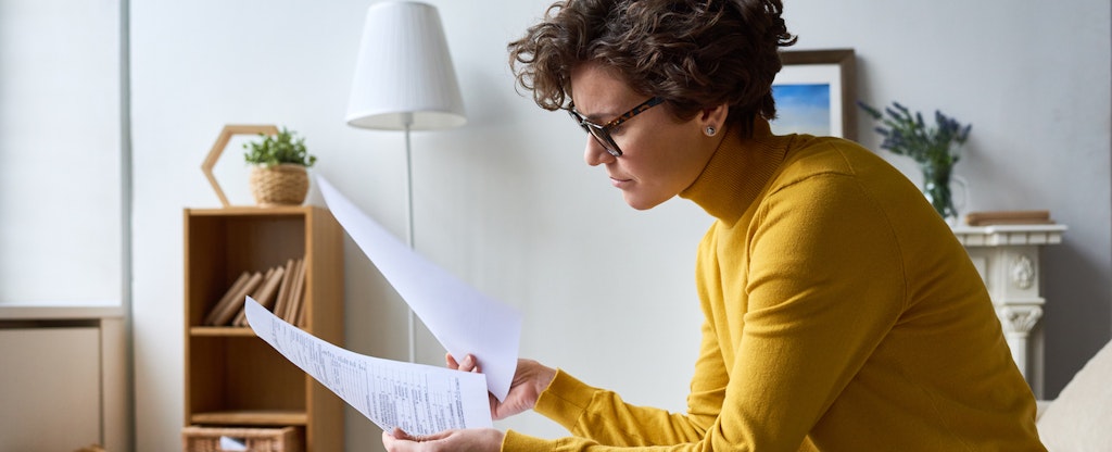 Woman sitting at home looking at documents she needs for filing back taxes