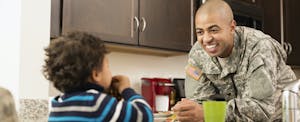 Father in military uniform in kitchen with young son in their home that they financed with a veterans united mortgage