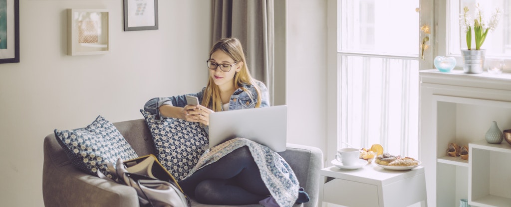 A young woman relaxes on the sofa with her digital tablet at home.