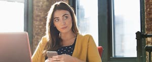 Young woman holding her cellphone and wondering if checking accounts are free