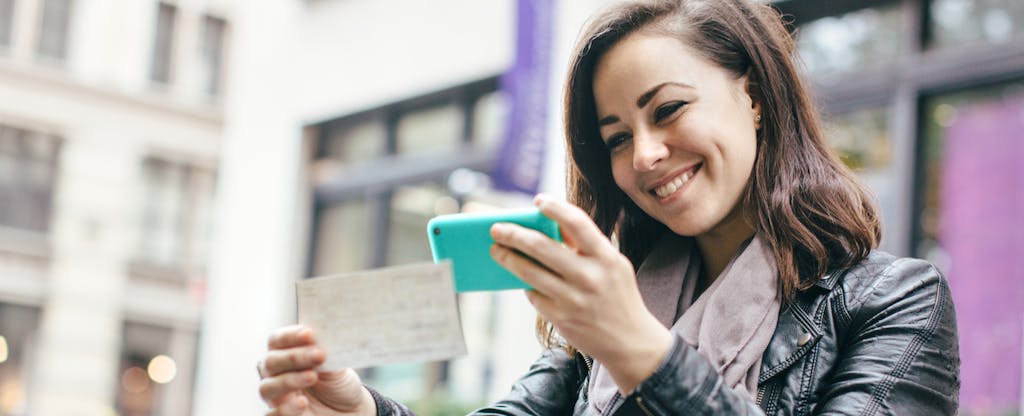 woman taking photo of check with mobile phone
