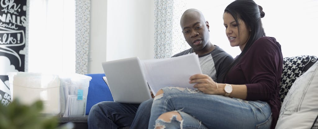 Couple with laptop discussing financial paperwork in living room