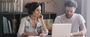 Young couple at home, looking up lenderfi mortgage on their laptop