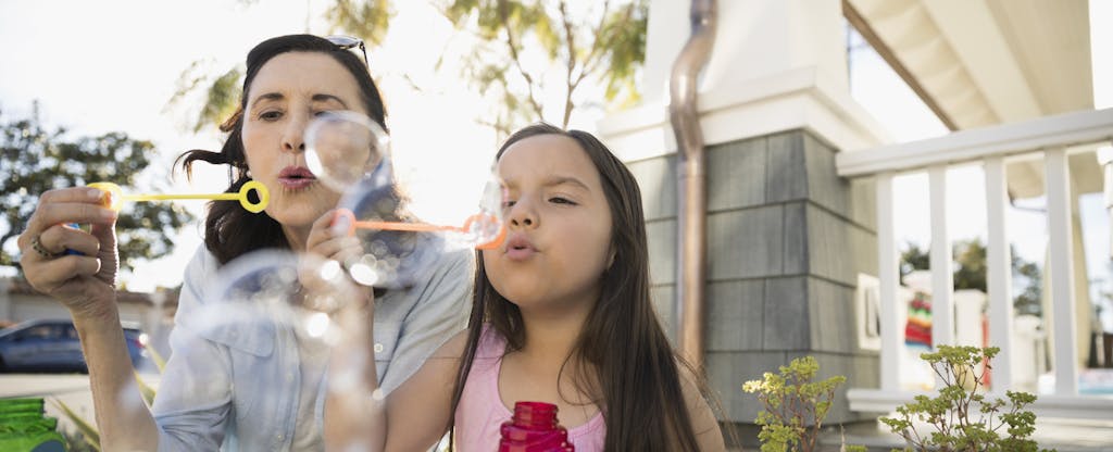 Mom and daughter in backyard blowing bubbles