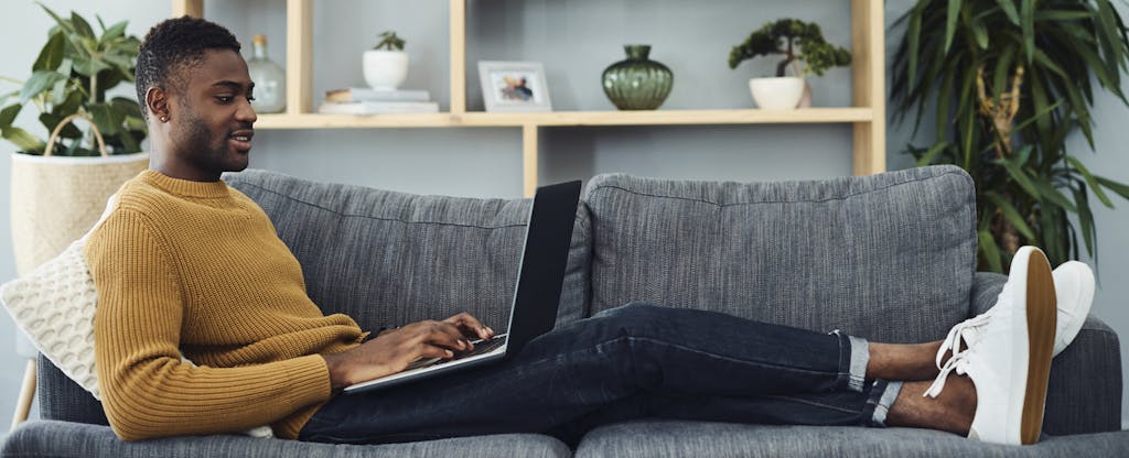 Man using a laptop on the couch while relaxing at home