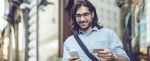 man holding phone and credit card smiling