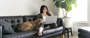 woman sitting on couch with laptop and dog