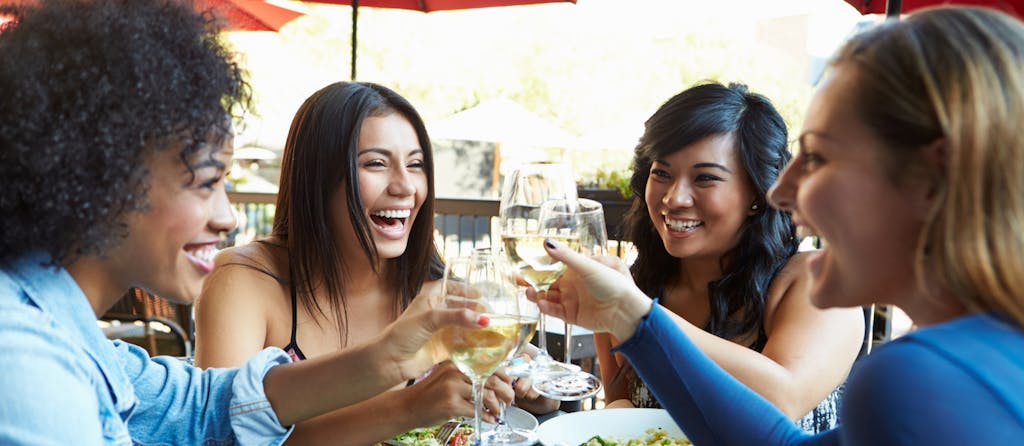 Happy Smiling Group Of Female Friends Enjoying Meal At Outdoor Restaurant