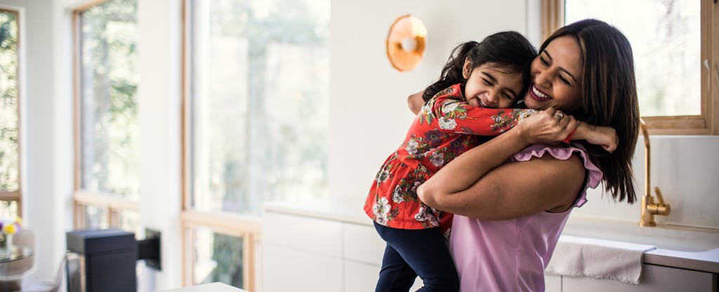 Mother and daughter embracing in kitchen