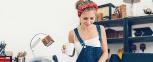 woman wearing overalls holding a coffee cup