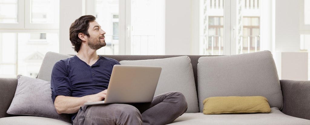 Man sitting on couch using laptop
