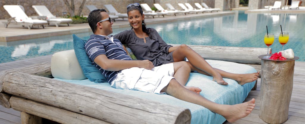 couple lounging by pool with cocktails