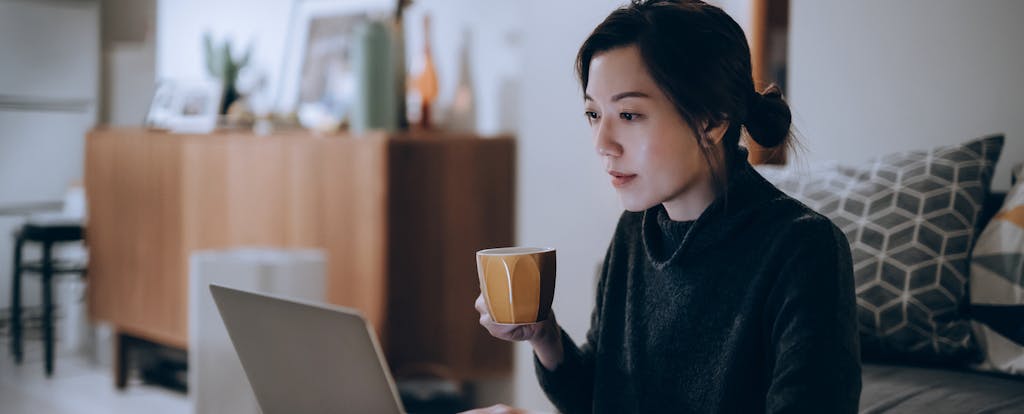 Woman holding mug while on her laptop concentrating