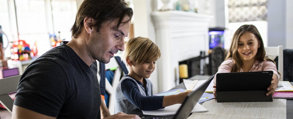 Father on laptop at home with kids