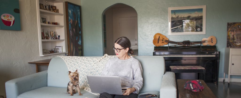 Woman sitting on couch with laptop looking at personal loan options.