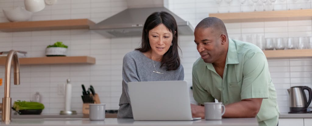 A couple at their kitchen countertop look into Citibank mortgage using a laptop.