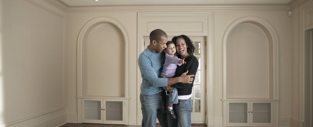 Man and woman holding their young child together, standing in their new home purchased with an M&T mortgage