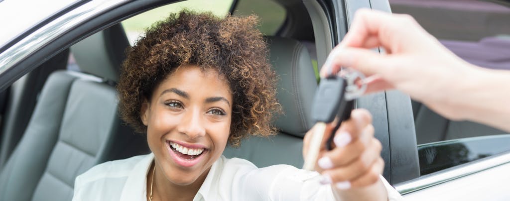 Smiling woman receiving keys to her new used car