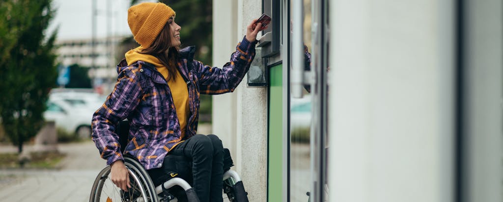 Young woman in a wheelchair using an ATM.