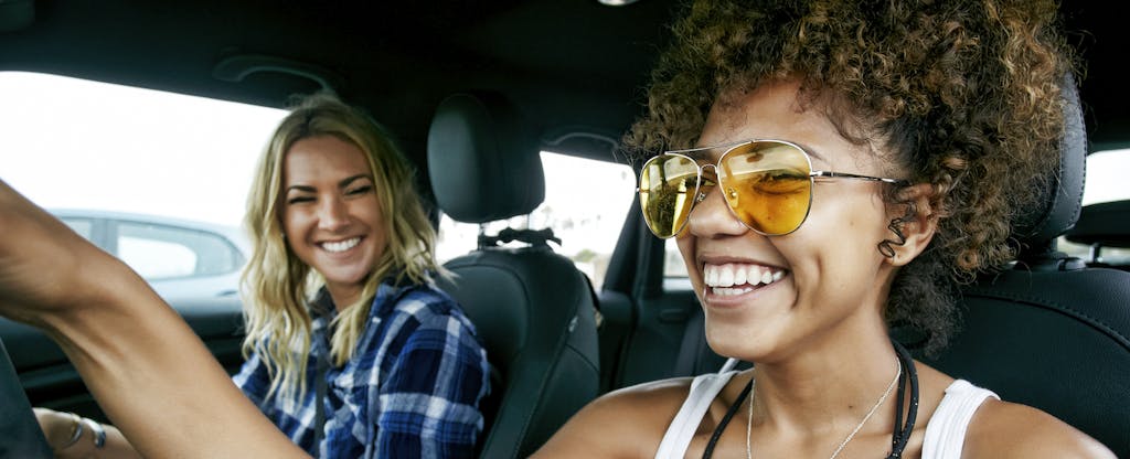 Two young women in a car, smiling and laughing