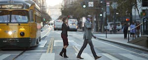 Two people talking on their cellphones cross the street in San Francisco's financial district.