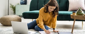 Woman checking bills while sitting on floor at home