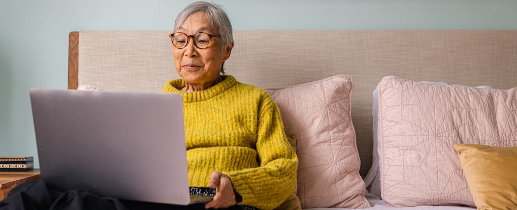 A seated woman with short gray hair uses a laptop to look into Fifth third personal loans.