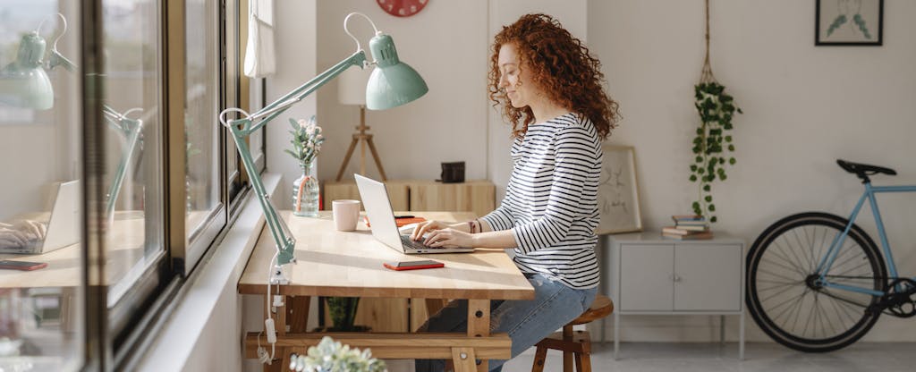 Woman sitting at a desk using a laptop computer while working from home.