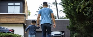 Man standing in his driveway with his young child