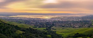 Sunset view of Fremont, California, from high up on a green hill