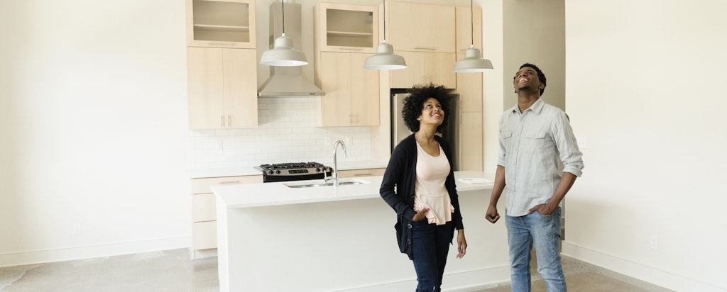 Couple standing in kitchen looking up at the ceiling in an empty new house