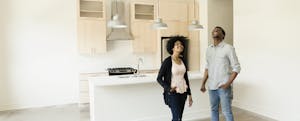 Couple standing in kitchen looking up at the ceiling in an empty new house