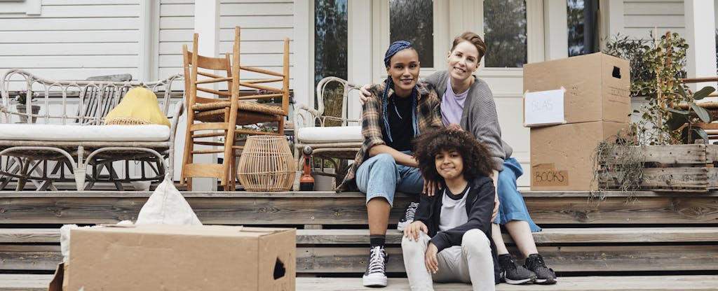 Young multiracial family sitting on the steps of their new home