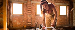 Woman working intently on her home renovation plan, in a sunny brick-walled room in her house