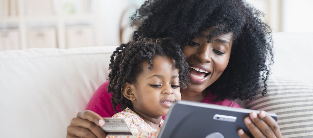 Mother and daughter on a couch with tablet and debit card banking online