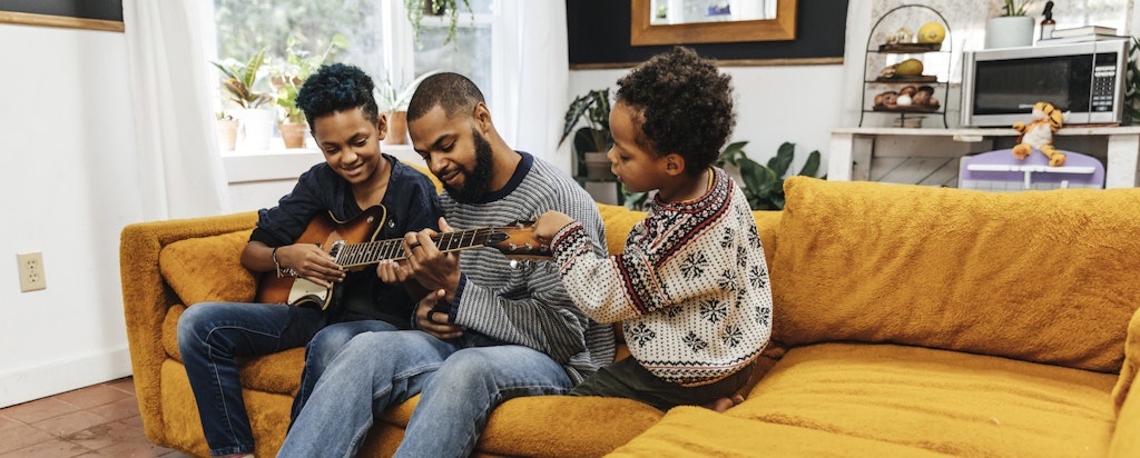 Dad playing guitar on the couch with kids at home