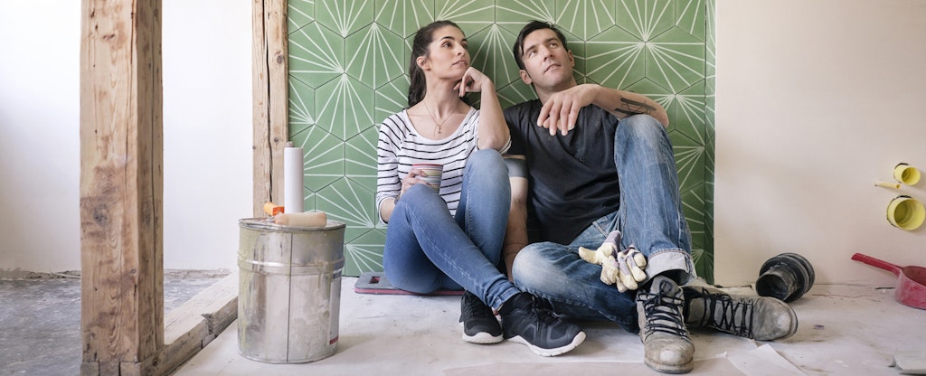 A couple lean against a freshly tiled bathroom wall contemplating the additional work that will be done using their PenFed HELOC.