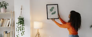 Woman hanging a picture in her home