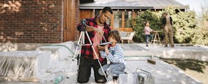 Father and young son working on a home-improvement project together in front of the family home
